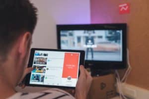 man browsing tablet sitting in front of TV, improve your organization's youtube channel